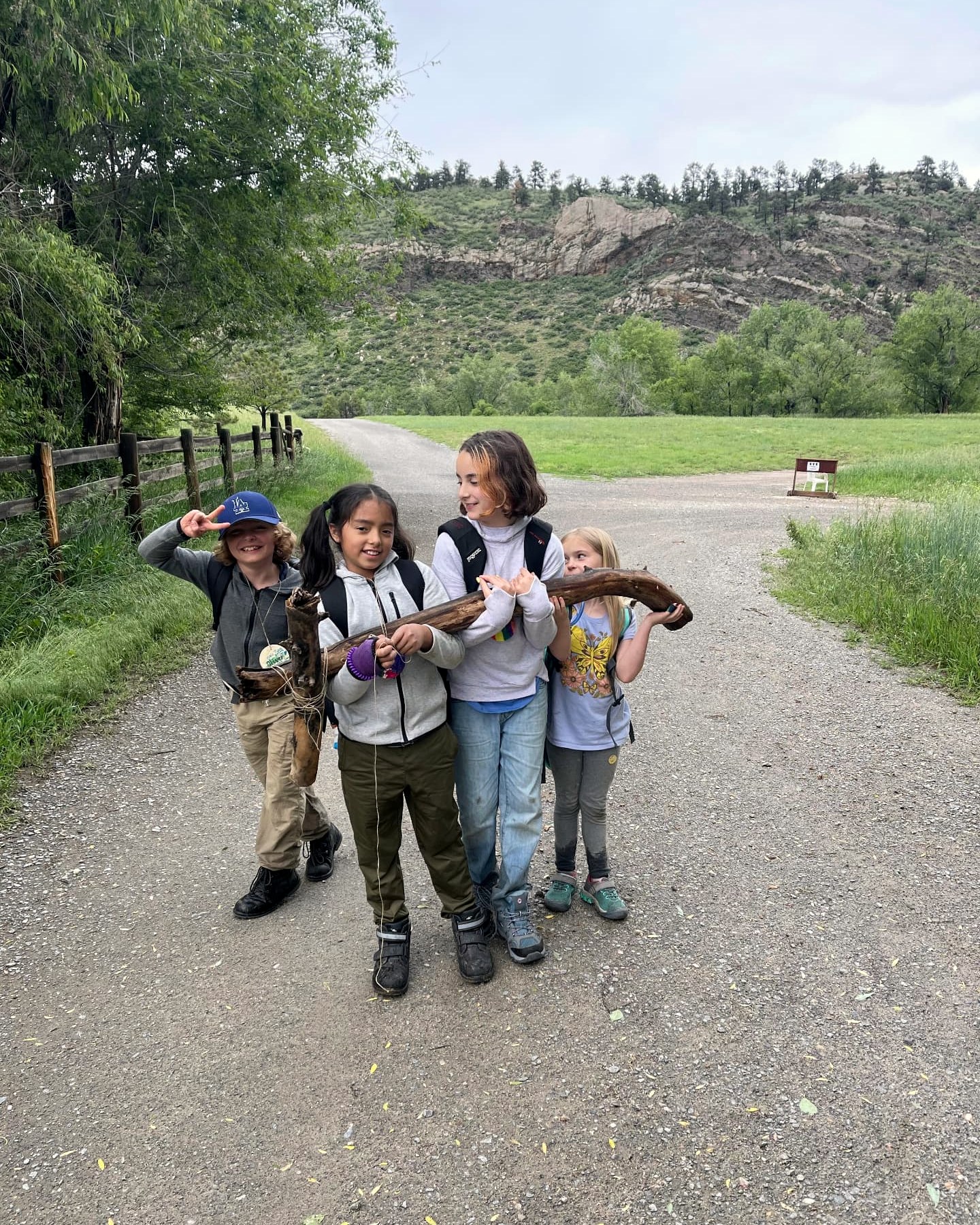 Students carrying a driftwood log together along a ranch road at Heart-J Center
